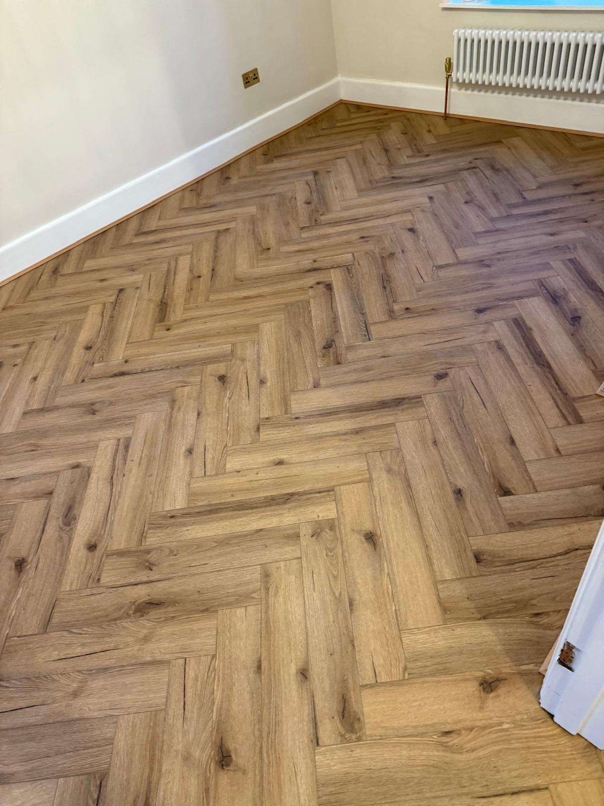 Oak-effect herringbone flooring fitted in a freshly decorated reception room