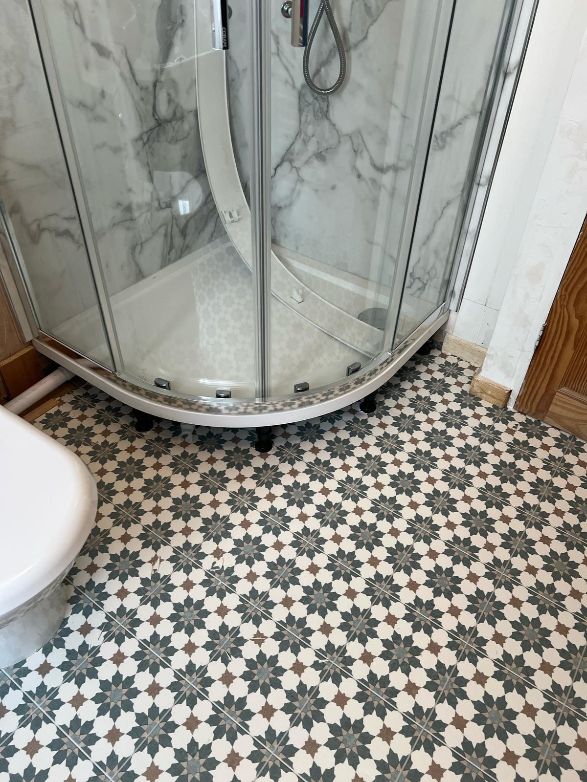 Patterned Victorian-style tiled bathroom floor around a shower enclosure
